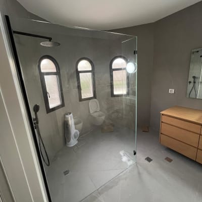 חדר רחצה עם מקלחון זכוכית, שירותים ומאוורר עומד