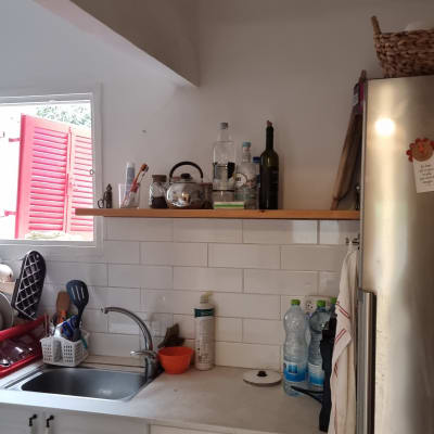 מטבח עם כיור, מדף עם בקבוקים וכלים שונים