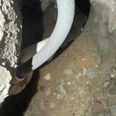 צינור פלסטיק בתוך חור בקיר עם אדמה