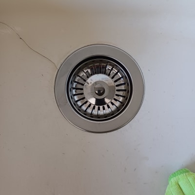 כיור עם מסננת נירוסטה ומטלית ירוקה