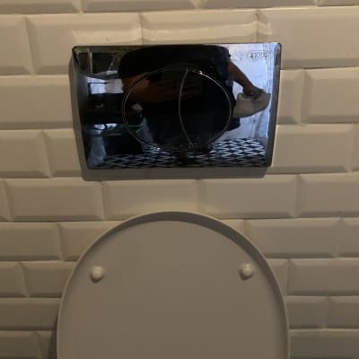 לחצן הדחה כסוף על קיר אריחים לבנים