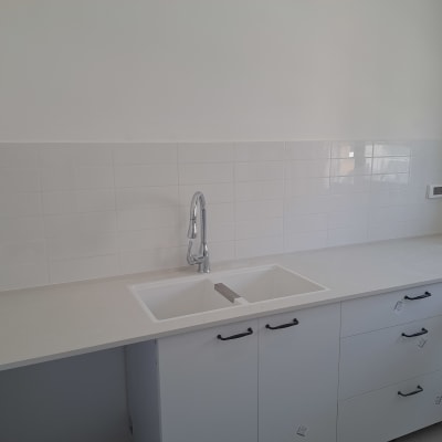 כיור וברז מותקנים במטבח חדש עם ארונות לבנים