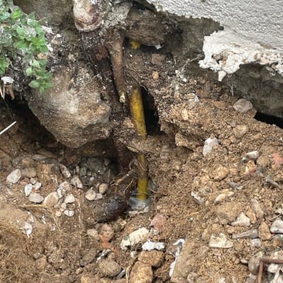 צינור צהוב שבור עם מים זורמים באדמה