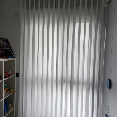 וילון לבן תלוי בחדר עם מדפים וצעצועים