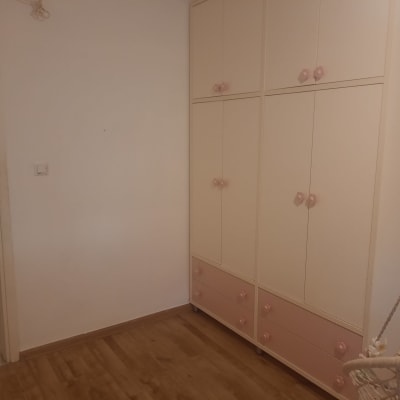 קירות צבועים בלבן בחדר ילדים מרוהט עם ארון בגדים