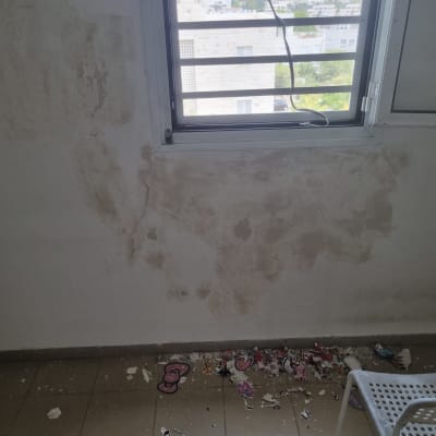 קיר עם כתמי צבע מתקלפים ליד חלון פתוח