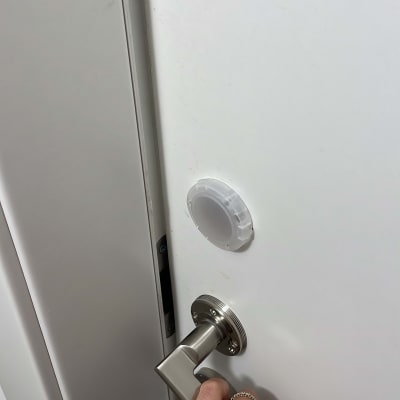 יד אוחזת בידית דלת מתכתית על דלת לבנה