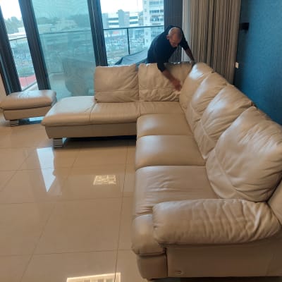 אדם מנקה ספה עם מטלית בחדר מגורים