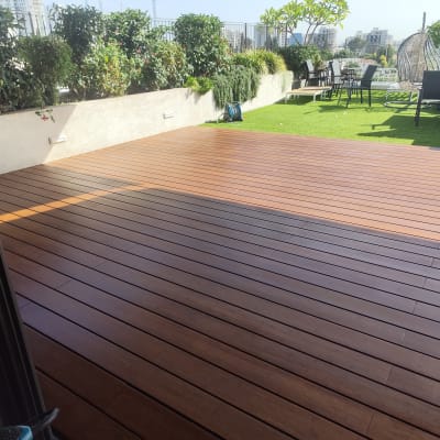 דק עץ בגינה עם ריהוט גן וצמחייה מסביב