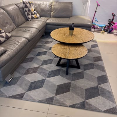 ספה אפורה עם שולחן עץ על שטיח גיאומטרי