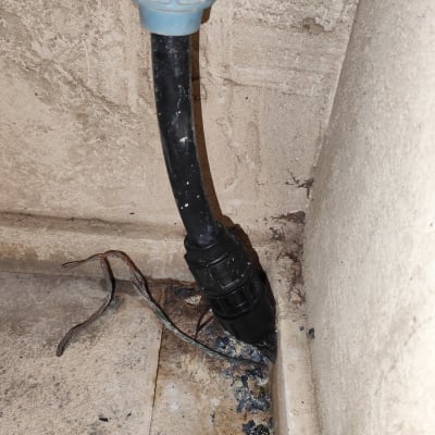 צינור שחור עם מחבר כחול על קיר בטון