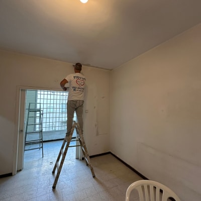 אדם על סולם צובע קיר בחדר מואר
