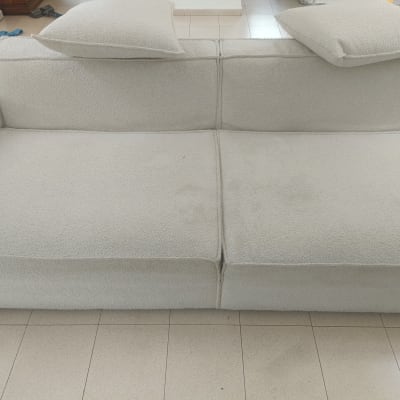 ספה בהירה עם כריות על רצפת אריחים