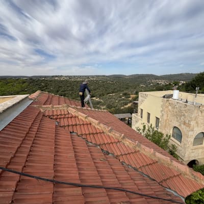 גג רעפים אדום עם אדם עובד על תיקון