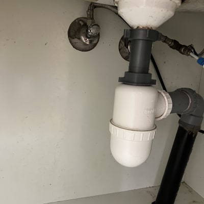 צנרת מתחת לכיור עם מחברים וצינור פלסטיק