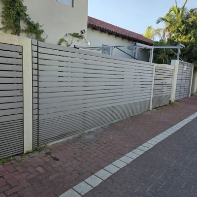 שער חשמלי אפור ליד בית עם גינה