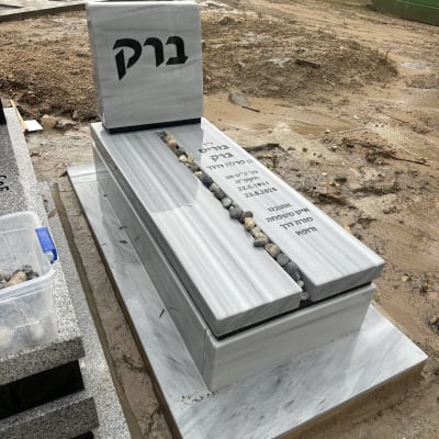 מצבה עם כיתוב בעברית ואבנים קטנות