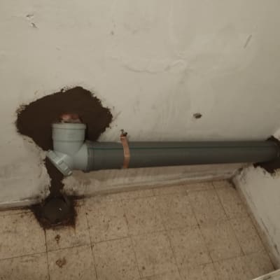צינור פלסטיק מותקן בקיר עם חיבורי ביוב