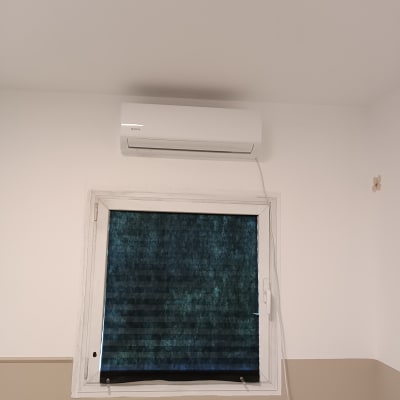 מזגן מותקן מעל חלון עם וילון כהה