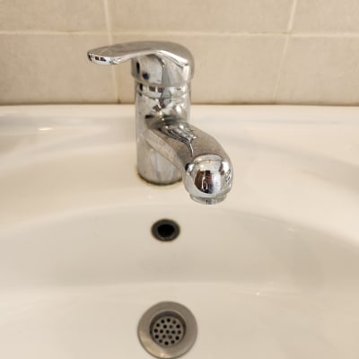 ברז כרום מעל כיור לבן עם ניקוז