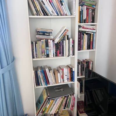 ספרים על מדף לבן, חלקם נוטים ליפול