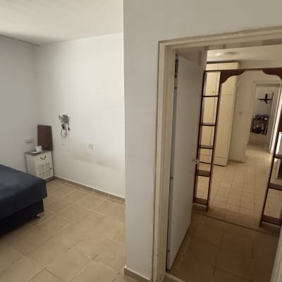 חדר ריק עם מיטה, חלון ודלת פתוחה