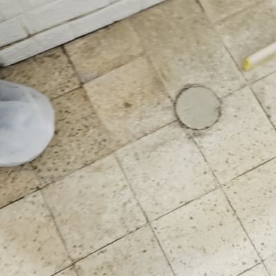 צינור לבן על קיר לבנים ורצפת אריחים