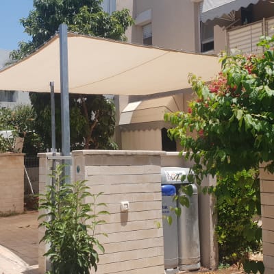 סוכך בד מתוח על עמודים בחצר בית