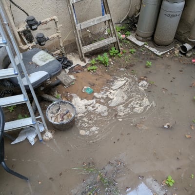 שטח חיצוני עם שלולית בוץ, סולם, כיסא וצינורות גז.