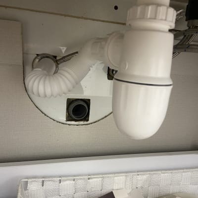 צינור ניקוז לבן מתחת לכיור עם חיבורים