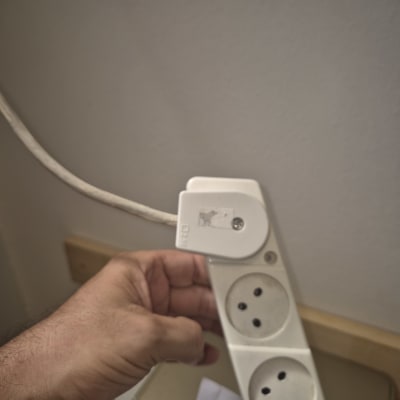 יד מחזיקה כבל חשמל ליד שקע חשמלי