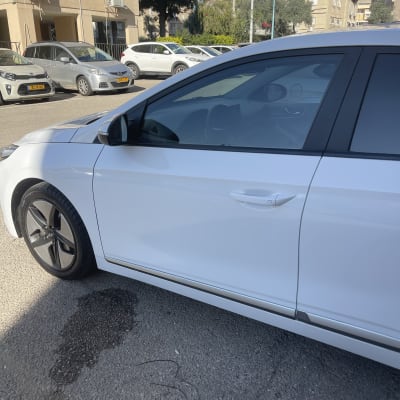 מכונית לבנה עם חלון כהה בחניה