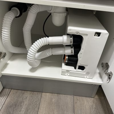 צנרת מתחת לכיור עם חיבורים לבנים וגמישים