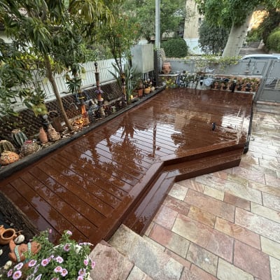 דק עץ בגינה עם עציצים ופרחים מסביב