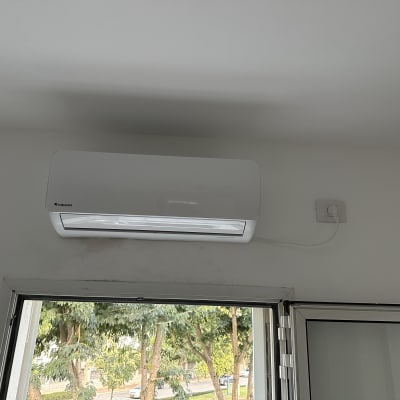 מזגן קיר לבן מותקן מעל חלון פתוח