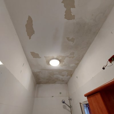 תקרה מתקלפת עם כתמי רטיבות בחדר אמבטיה