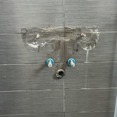 ברזים וצנרת על קיר אריחים אפור