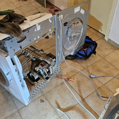 מכונת כביסה פתוחה עם כלים לתיקון על הרצפה