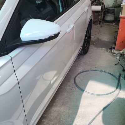 מכונית לבנה עם צינור על רצפת מוסך