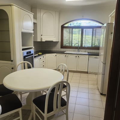 מטבח עם שולחן עגול, כיסאות וארונות לבנים