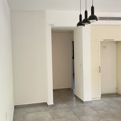 קירות ותקרה צבועים בלבן בדירה ריקה עם תאורה מודרנית וריצוף אפור