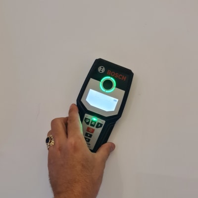 יד מחזיקה מכשיר בוש על קיר לבן