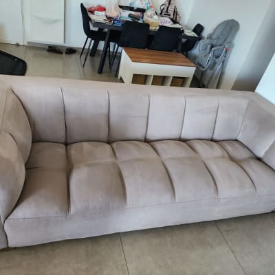 ספה בהירה בחדר עם שולחן וכיסאות ברקע