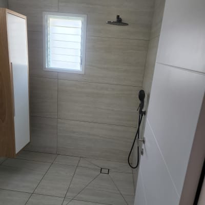 חדר אמבטיה נקי עם מקלחת וקיר אריחים