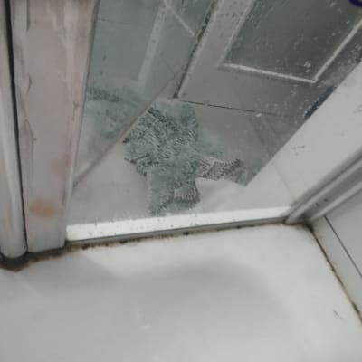 דלת מקלחת עם זכוכית ומגבת על הרצפה