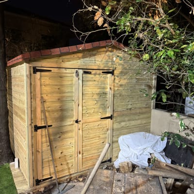 מחסן עץ עם דלתות כפולות וכלי עבודה בגינה