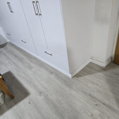 רצפת פרקט אפורה ליד ארון לבן ודלת עץ