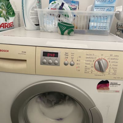 מכונת כביסה עם חומרי ניקוי על המדף