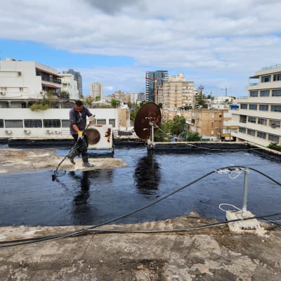 אדם מורח חומר איטום על גג שטוח