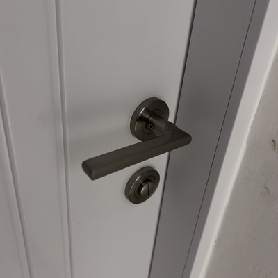 ידית דלת מתכתית על דלת לבנה